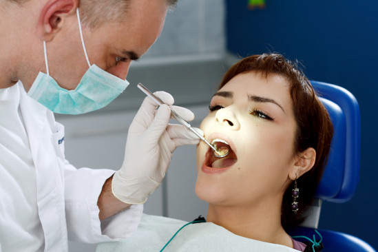 Zahnarzt untersucht Patientin im Mund